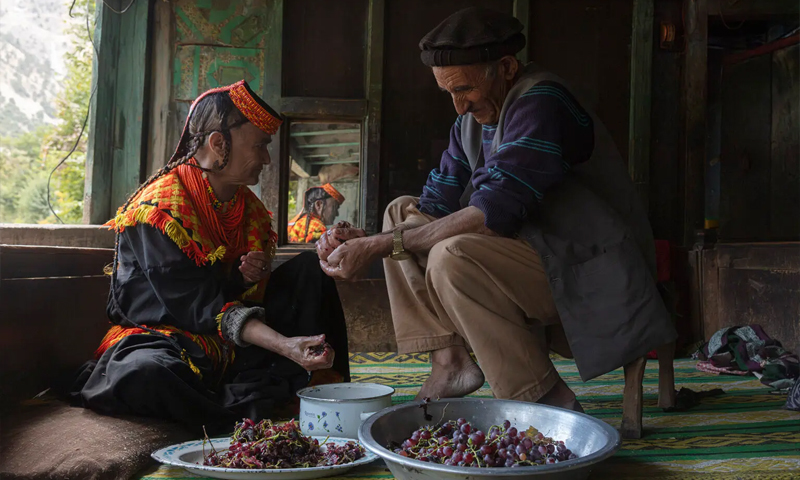 Kui Begum helps her husband during the traditional winemaking process in Bumburet Kalash, Picture by Komal Ghazaali، 2025