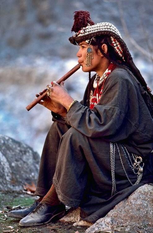 A Kalash girl playing a flute in Chitral